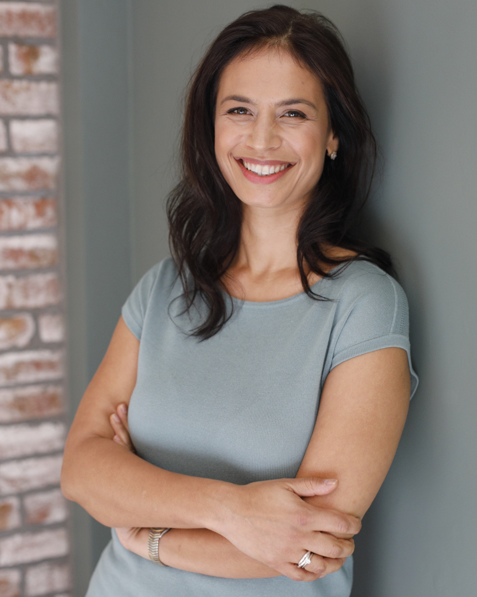 Portrait of Nanda Frances Bergstein, leaning against a wall in natural light.